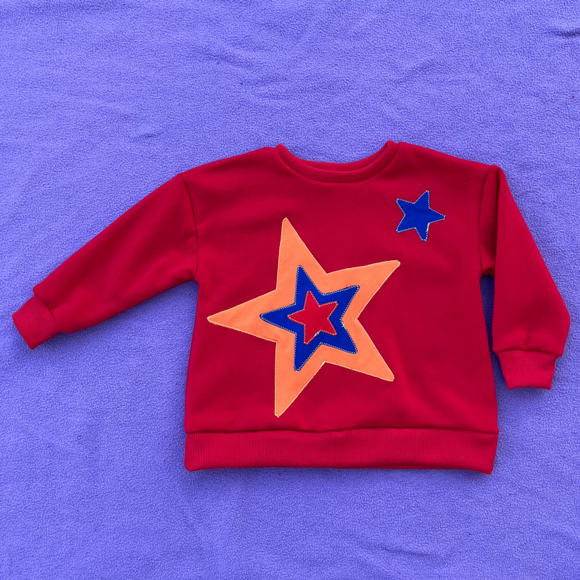 Red sweatshirt with star design on a purple background
