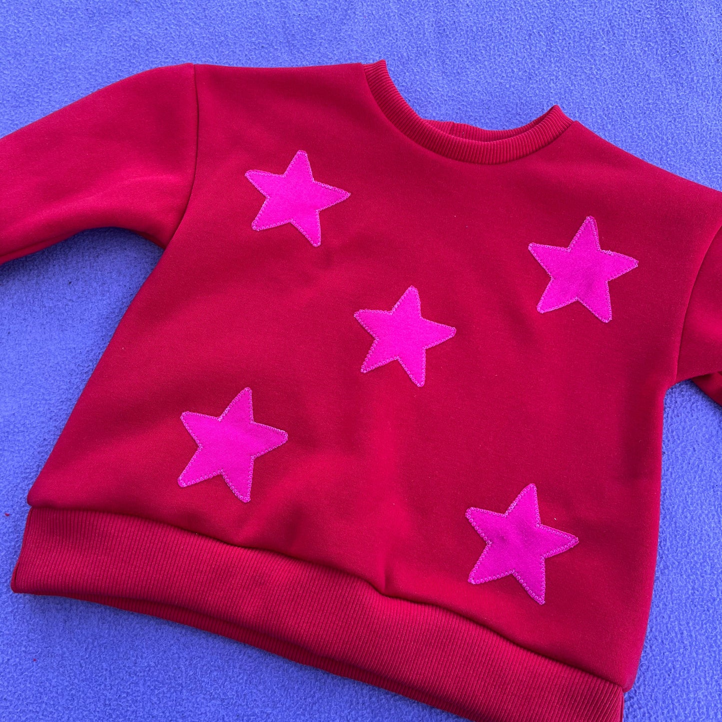 red sweatshirt with hot pink stars on a purple background
