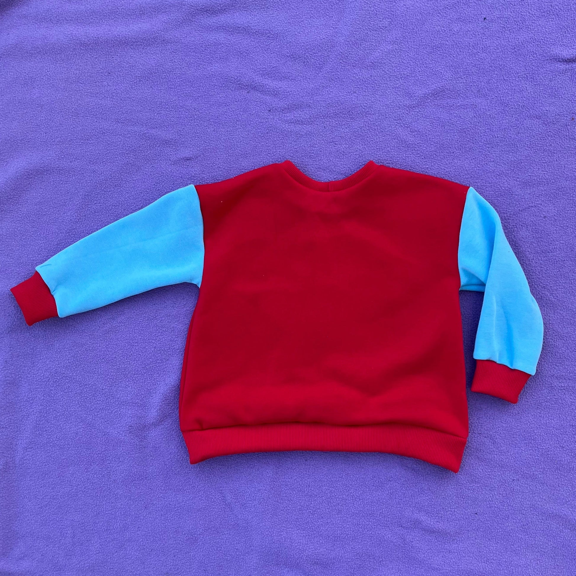 Red and blue sweater on a purple blanket