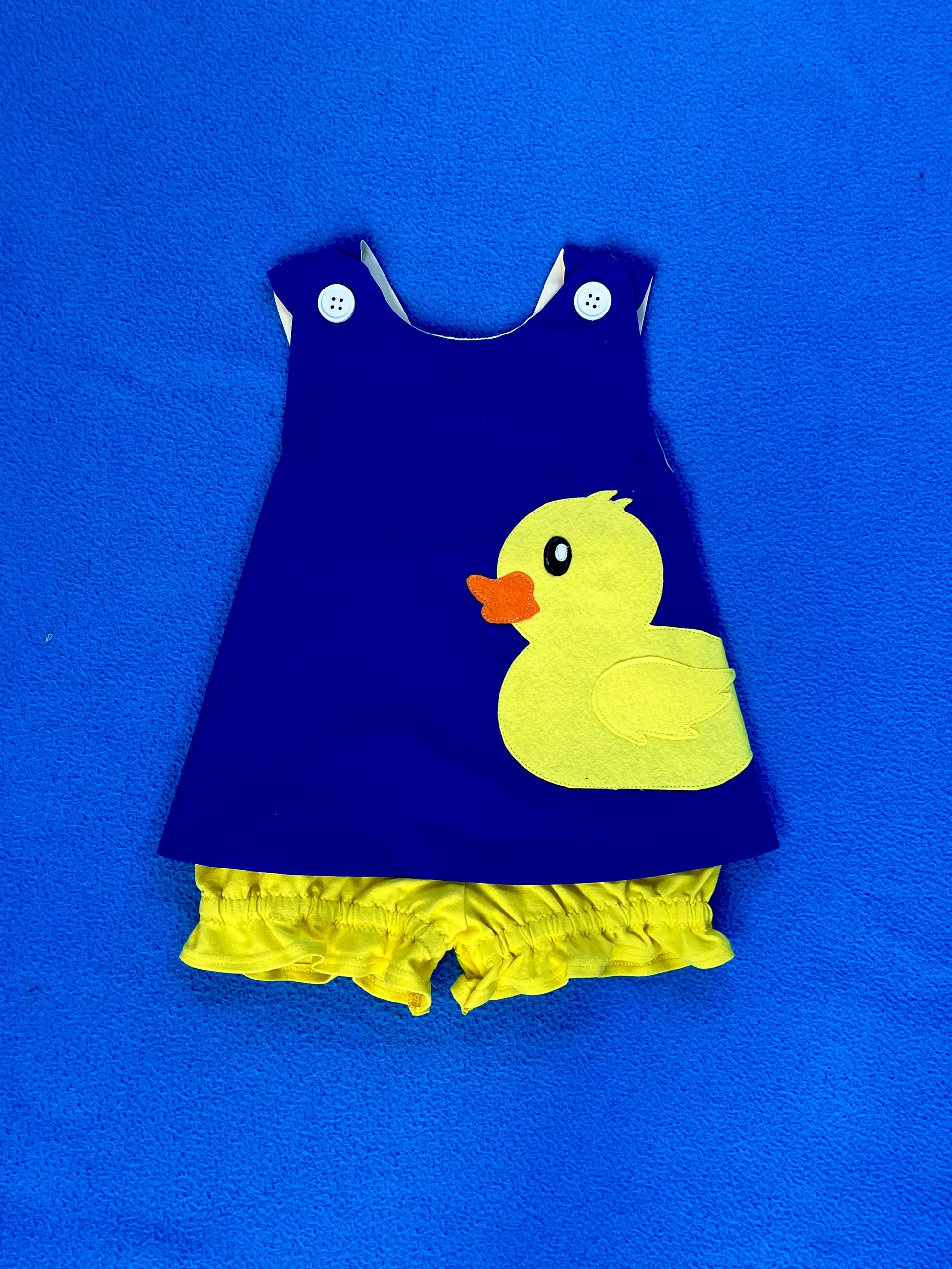 Navy blue dress with yellow duck design on a blue background