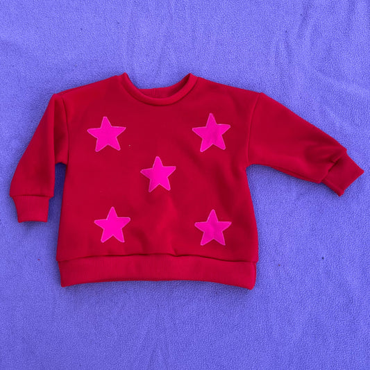 Red sweater with pink stars on a purple surface